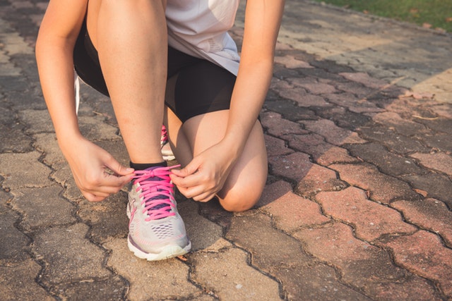 Exercising woman tightening sneakers laces